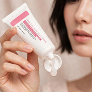 Mossicare Collagen Jelly Cream – A woman's hand holding an open tube of PDRN Collagen Jelly Cream with a drop of gel dripping from the nozzle, her face softly blurred in the background.