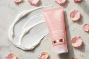 Mossicare Collagen Night Wrapping Mask – pink squeeze tube lying on a light marble surface with a swirl of white cream and scattered pink rose petals